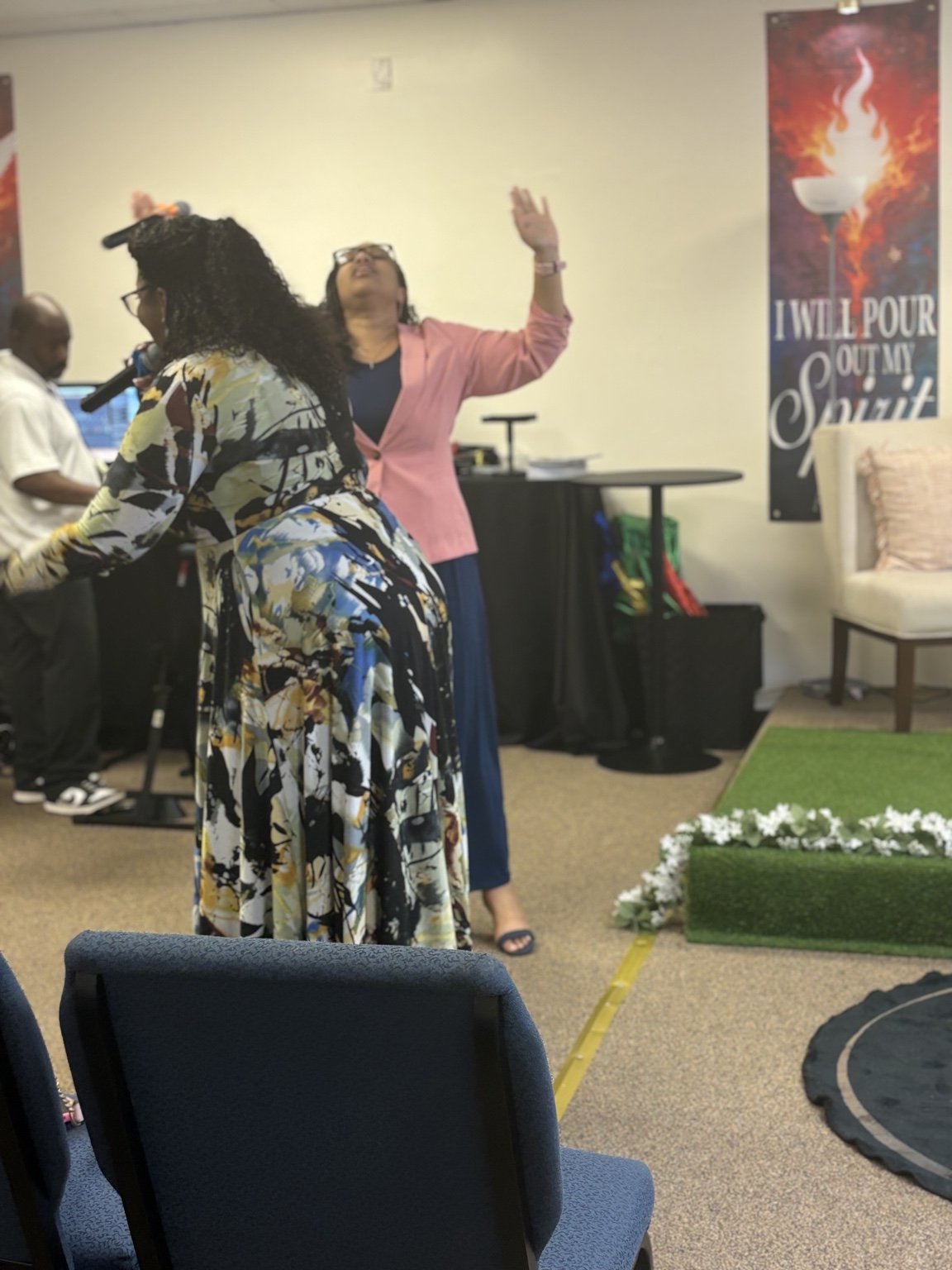 A worship leader singing as a congregant raises her hand