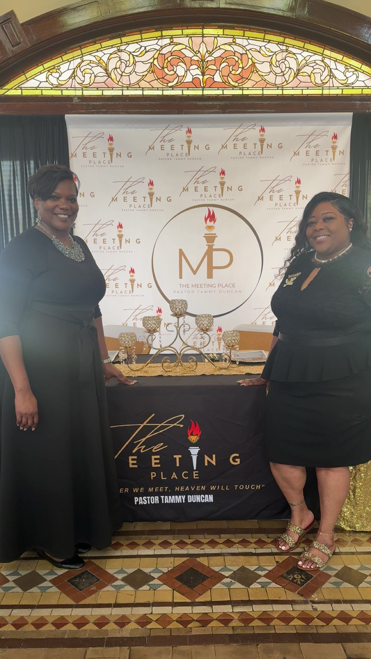 Two women standing together in front of a ministry backdrop