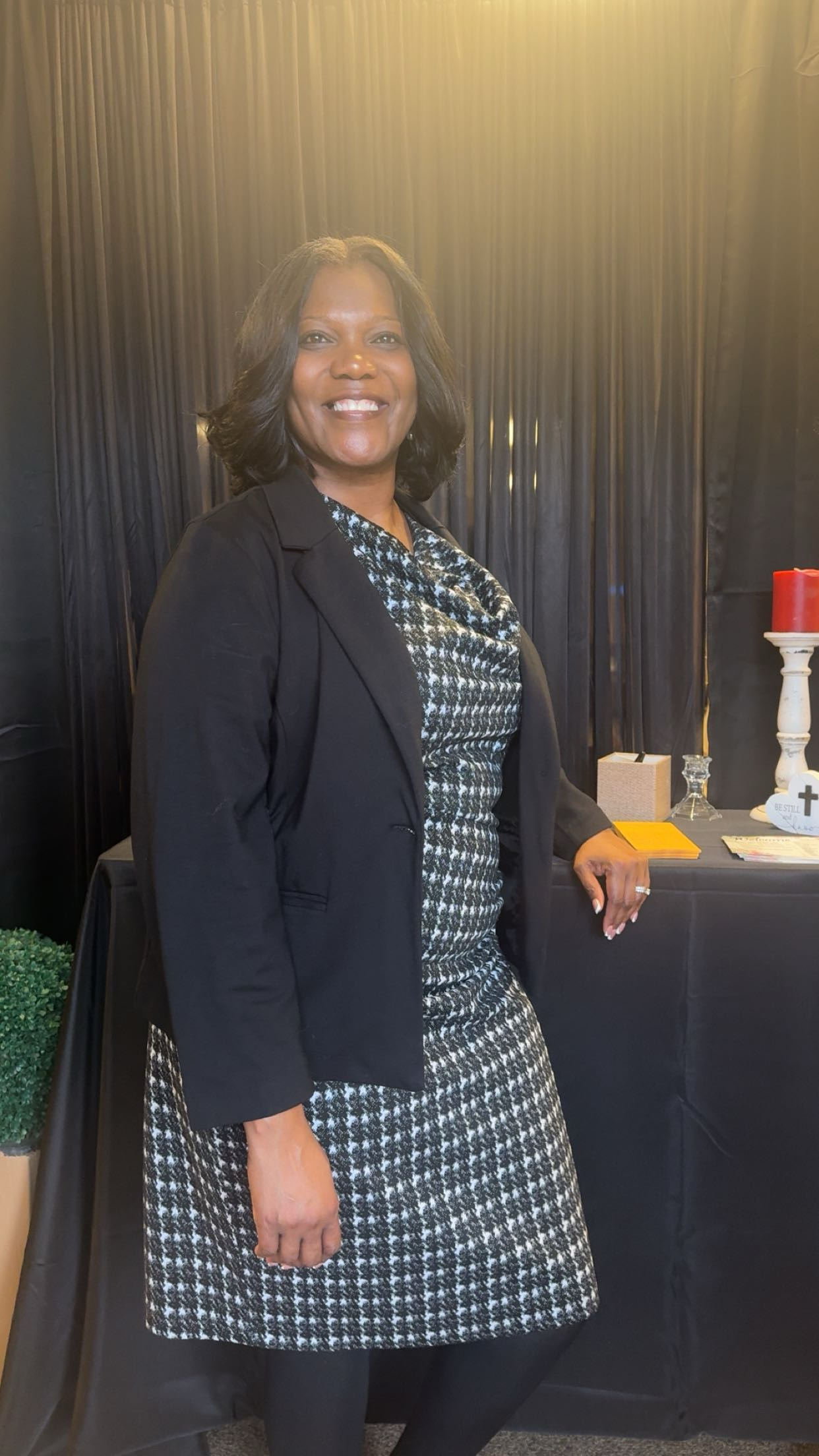 A woman smiling in a black and patterned outfit